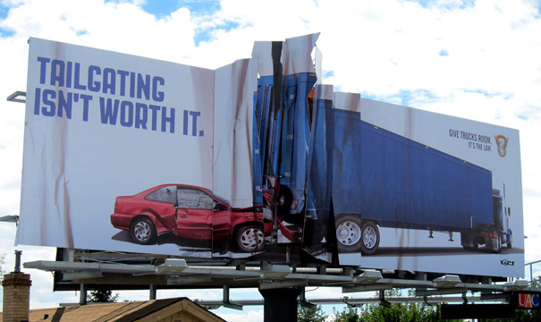 Broken billboard ad with car and truck images.