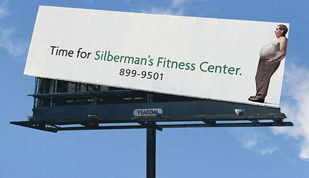 A billboard ad for Silberman's Fitness Center with a fat man image.