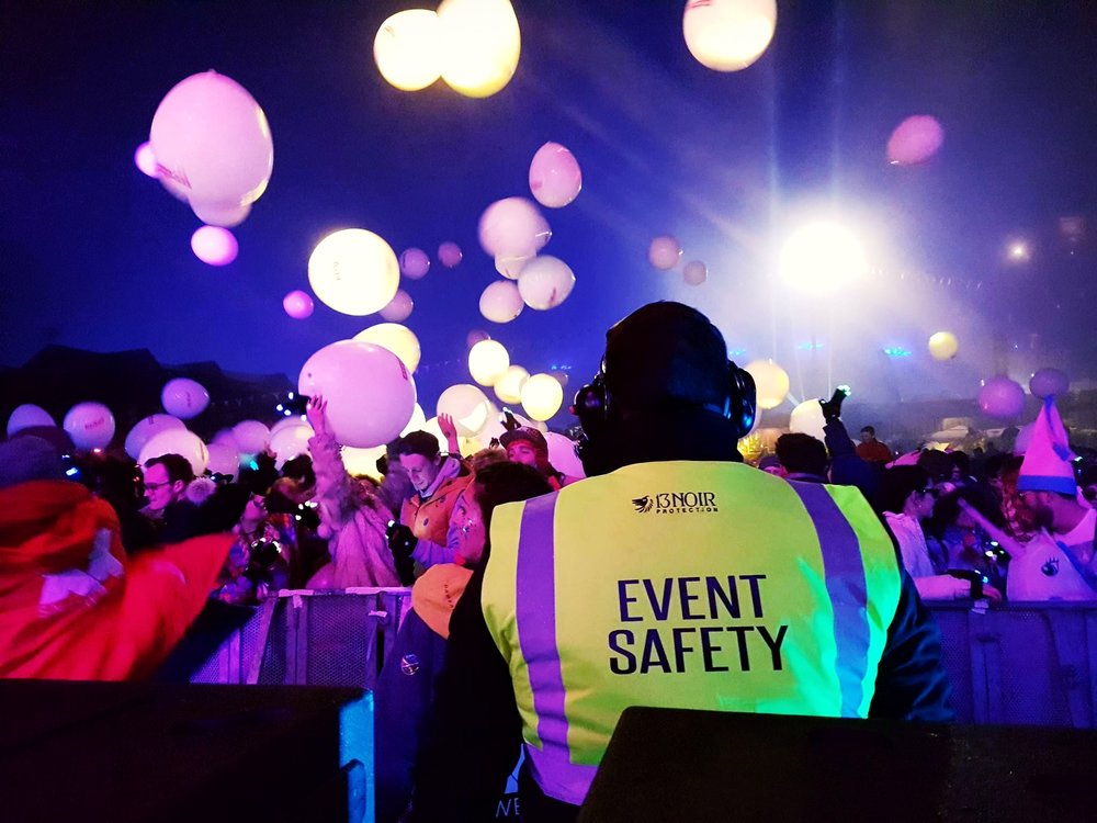 a man wearing event safety uniform while watching people in the event