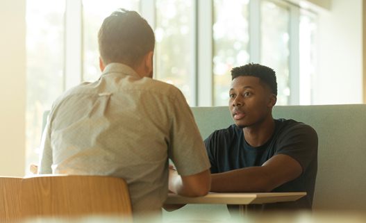 a man talking to a boy at a table in a building