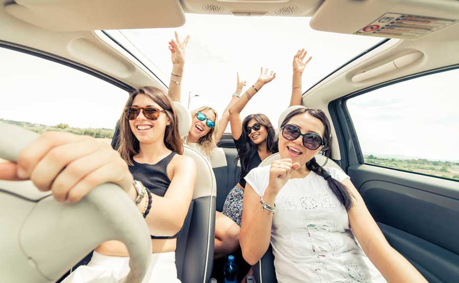 four girls having fun driving a car