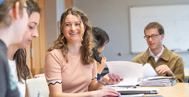 a female student holding a piece of paper smiling at her colleagues