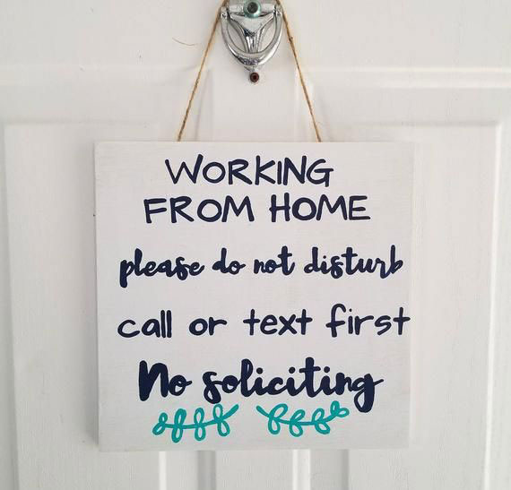 a white sign handing on a door that says "Working from home"
