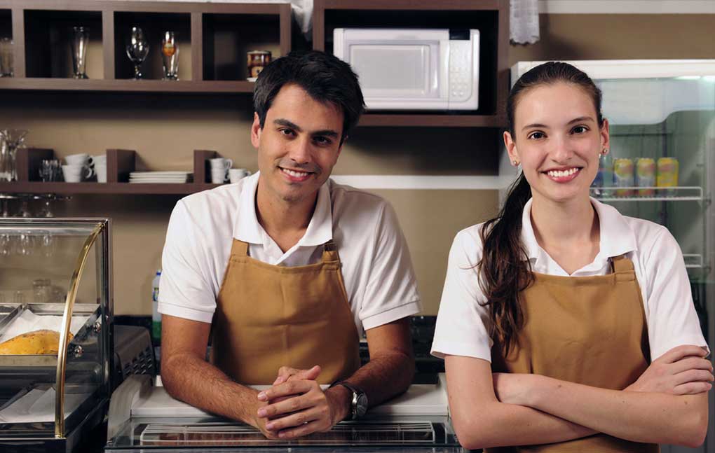 two-employees-with-aprons-on-smiling-at-the-camera-in-a-store